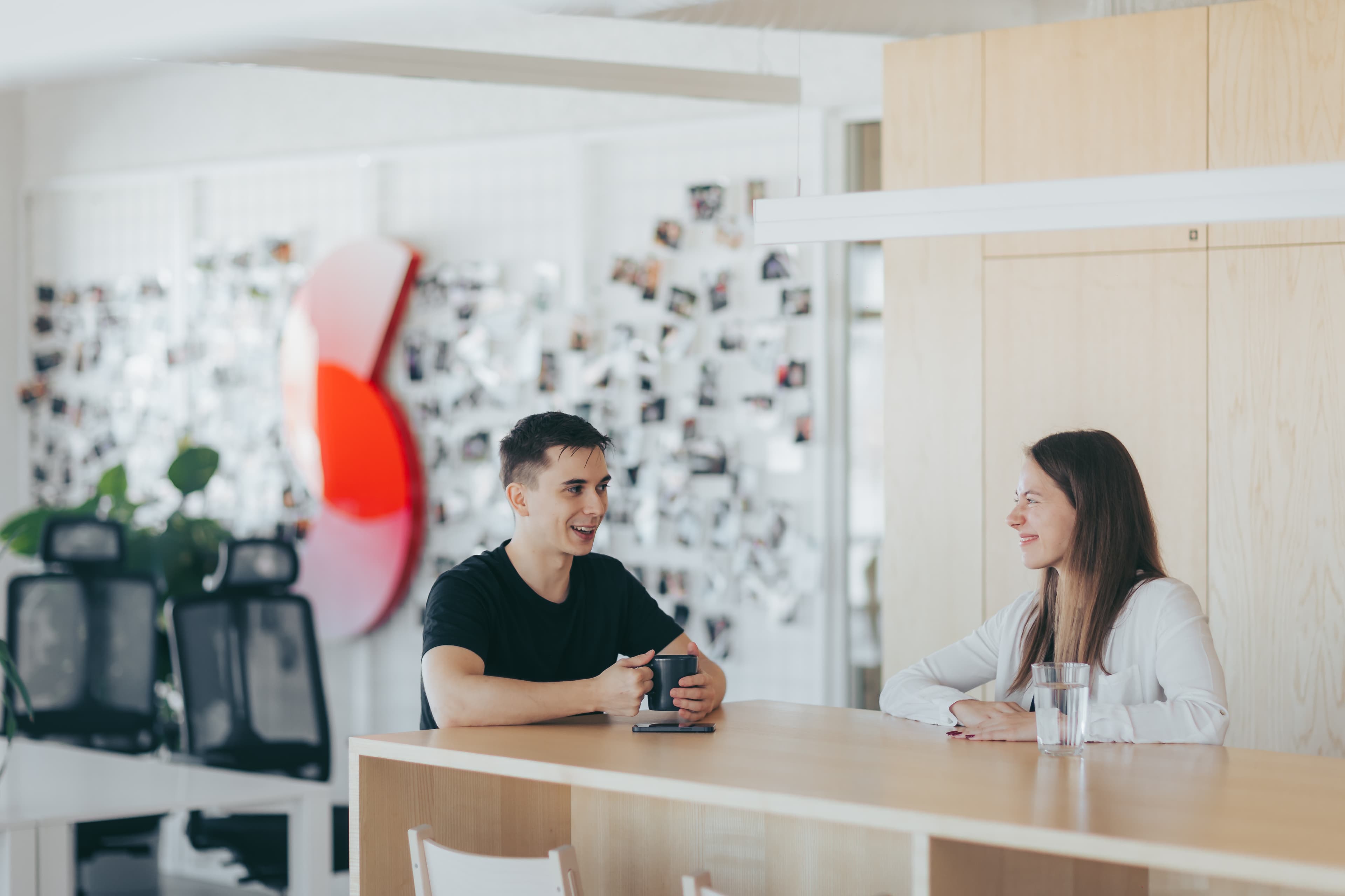 Žaneta grinning and engaging in a lively discussion with data scientist Erik at Sudolabs' common office space