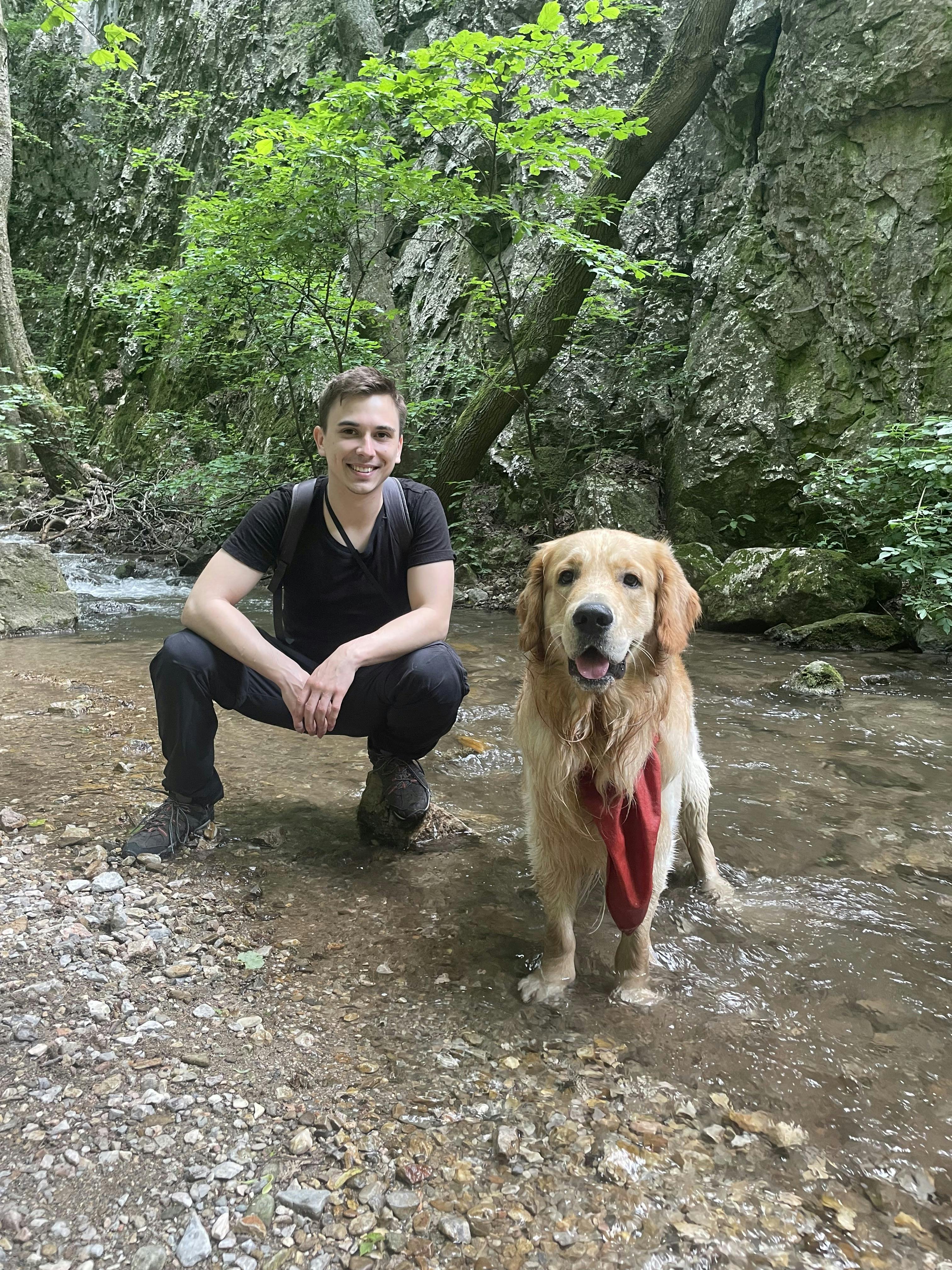 Erik Kandalík and his loyal Golden Retriever, Gaston, enjoying a peaceful moment in nature. They are surrounded by greenery, highlighting their bond in the great outdoors.